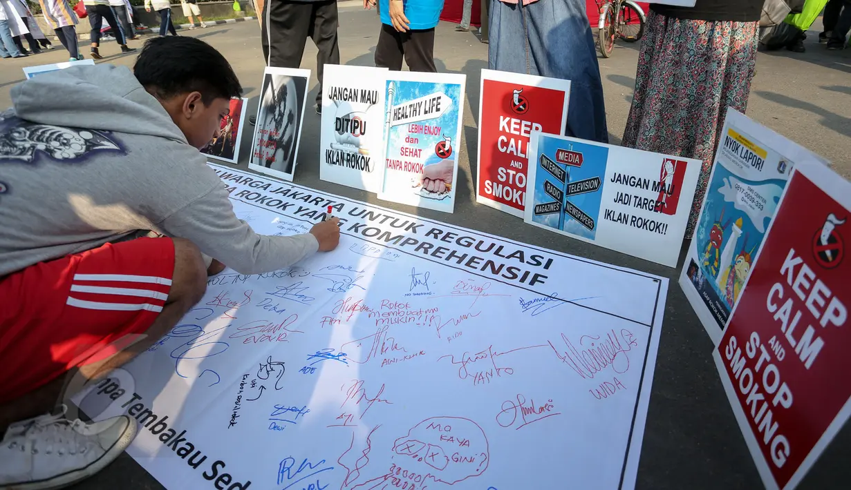 Warga membubuhkan tanda tangan dukungan di sebuah spanduk saat aksi peringatan Hari Tanpa Tembakau di Bundaran HI, Jakarta, Minggu (31/5/2015). (Liputan6.com/Faizal Fanani)