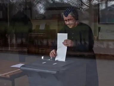 Seorang wanita memasukkan surat suara ke kotak suara saat pemilihan umum Belanda di sebuah sekolah yang dijadikan Tempat Pemungutan Suara (TPS) di Staphorst, Rabu (15/3). Kotak suara yang tersedia terbuat dari tempat sampah. (AP Photo/Muhammed Muheisen)
