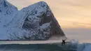 Seorang peselancar tengah beraksi di kawasan pantai  Flackstad, dekat Ramberg, kepulauan Lofoten, Arctic Circle, (9/3/2016). (AFP/Olivier Morin)