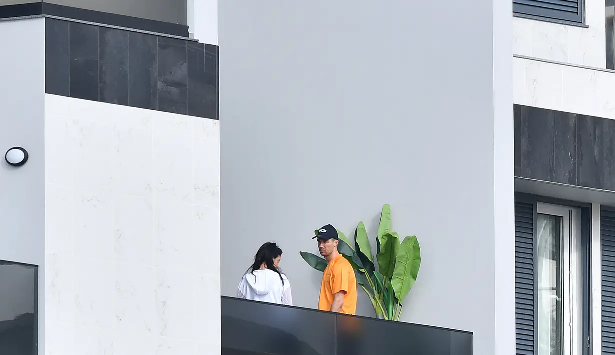 Cristiano Ronaldo dan Georgina Rodriguez berdiri di balkon di Funchal pada 13 Maret 2020. Ronaldo juga menyatakan terima kasihnya pada para tenaga medis, dokter dan perawat yang telah membantu proses persalinan. (AFP/RUI SILVA)