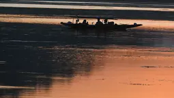 Nelayan menunggu di perahu kecil setelah memancing di Danau Dal saat matahari terbenam di Srinagar (9/9/2019). Di Sepanjang tepi Danau Dal terdapat Ghate yang merupakan tempat bersandarnya Shikara. (AFP Photo/Tauseef Mustafa)