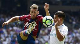 Pemain Levante, Ivan Lopez (kiri) menghalau bola dari kejaran pemain Real Madrid, Theo Hernandez pada lanjutan La Liga di Santiago Bernabeu stadium, Madrid (9/9/2017). Madrid bermain imbang 1-1. (AFP/Pierre-Philippe Marcou)