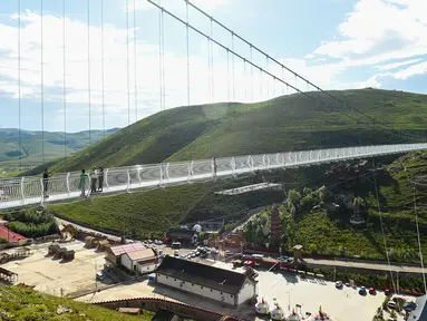 Wisatawan berjalan di atas jembatan gantung berlantai kaca di kawasan wisata nasional Hongshiya di Wilayah Zhuozi, Ulanqab, Daerah Otonom Mongolia Dalam, China utara, pada 15 Agustus 2020. (Xinhua/Peng Yuan)