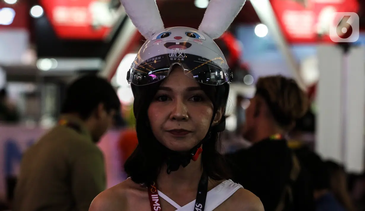 Seorang wanita mengenakan helm pada hari kedua pameran Indonesia International Motor Show (IIMS) 2023 di JIExpo Kemayoran, Jakarta Pusat, Jumat (17/2/2023). IIMS 2023 yang berlangsung hingga 26 Februari mengangkat tema "Bringing Opportunity for Otomotive Society Together" (BOOST) dan menghadirkan sekitar 40 merek otomotif dengan menampilkan produk dan konsep terbaru. (Liputan6.com/Johan Tallo)