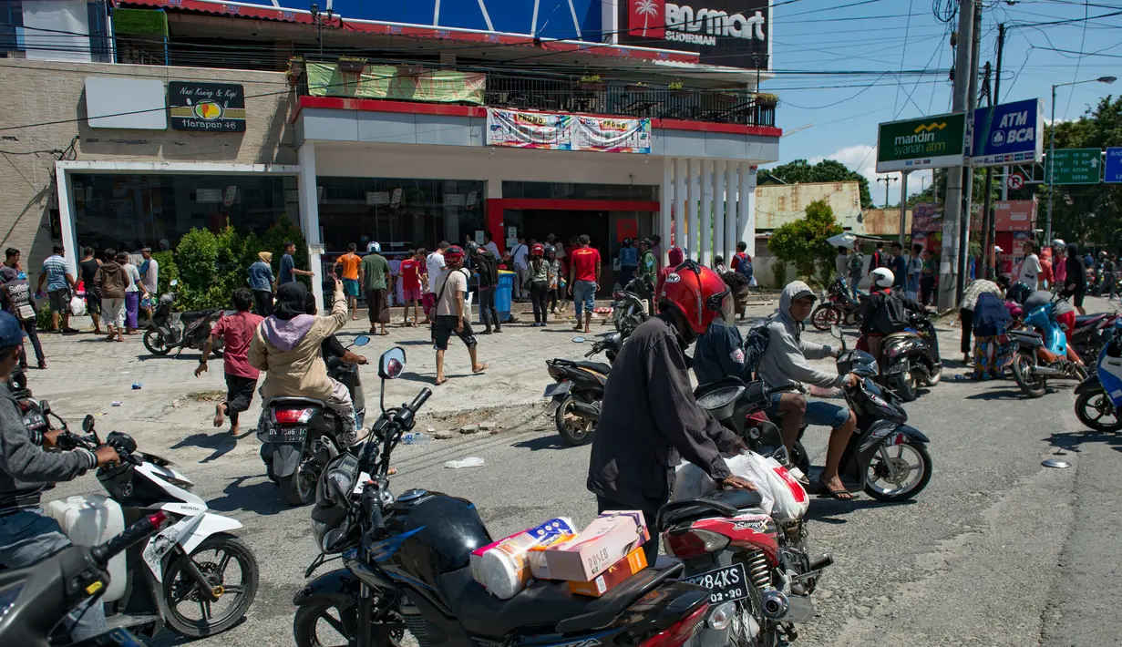 Warga menjarah kebutuhan pokok dari toko swalayan setelah gempa kuat dan tsunami mengguncang Kota Palu di Sulawesi Tengah, Minggu (30/9). Warga terpaksa mengambil karena mereka juga membutuhkan makanan dan air bersih. (AFP PHOTO/BAY ISMOYO)