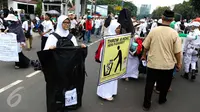 Sejumlah relawan membawa kantong plastik besar dan spanduk bertuliskan "Throw A HOAX, Here Please" di tengah aksi damai 4 November di Jakarta, Jumat (4/11). Mereka mengumpulkan sampah yang dibuang anggota ormas. (Liputan6.com/Faizal Fanani)