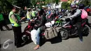 Petugas memeriksa surat pengendara sepeda motor pada operasi lalu lintas di Abu Bakar Ali, Yogyakarta, (19/5). Operasi ini untuk menekan angka kecelakaan, petugas memberikan surat tilang di tempat kepada pelanggar lalu lintas. (Liputan6.com/Boy Harjanto)