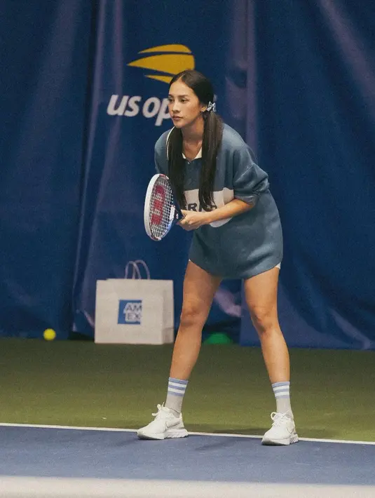 Anya Geraldine saat berkesempatan turun langsung ke lapangan turnamen tenis US Open 2022. Pemilik nama lengkap Nur Amalina Hayati ini tampil memakai kaus oversize, short pants, dan sneakers  dengan rambut dikuncir dua. Penampilan Anya ini sangat cantik natural. (Instagram/anyageraldine)