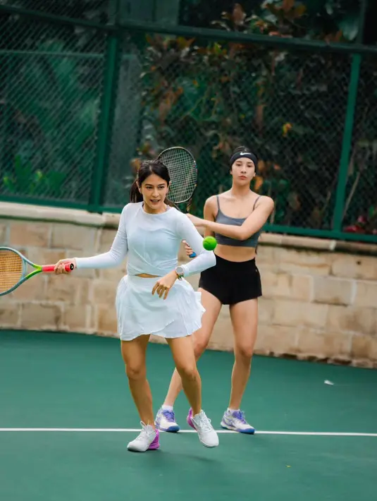Senyum sumringah, Dian mengenakan long sleeve biru muda dengan rok tennis dan sneakers dual tone [@therealdisastr]