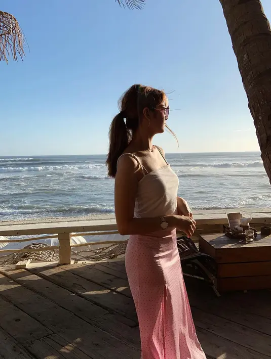 Saat ingin tampil lebih girly, tingkatkan gaya tampilan tank top putih dengan rok midi warna pink yang sedang tren.  (Foto: Instagram @danniasalsabilla)
