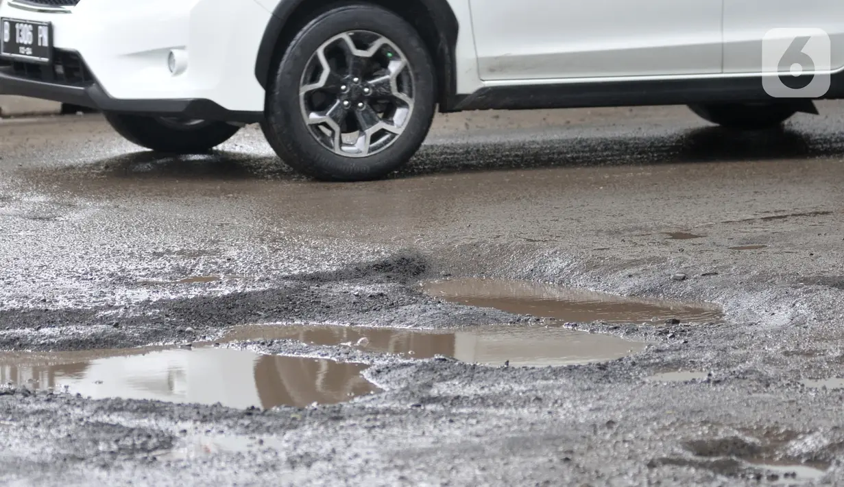 Kendaraan melintas dekat jalan berlubang di kawasan Kelapa Gading, Jakarta, Minggu (1/3/2020). Kepala Dinas Bina Marga DKI Jakarta Hari Nugroho mengatakan banjir pada Februari 2020 merusak 495 jalan Ibu Kota dengan 3.290 titik lubang yang tersebar di lima wilayah. (merdeka.com/Iqbal Nugroho)