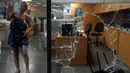 Seorang karyawan bank memberi isyarat, saat dia berdiri di samping jendela yang dirusak oleh deposan untuk keluar dari bank, Beirut, Lebanon, Rabu (14/9/2022). Setelah kejadian tersebut Hafez langsung berubah menjadi pahlawan rakyat Lebanon di media sosial. (AP Photo/Hussein Malla)