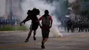 Para pengunjuk rasa melempar batu ke polisi anti huru-hara saat melakukan aksi protes pada peringatan Hari Buruh di San Juan, Puerto Rico (1/5). Hari Buruh yang jatuh pada tanggal 1 Mei ini diperingati di berbagai negara. (AFP/Ricardo Arduengo)