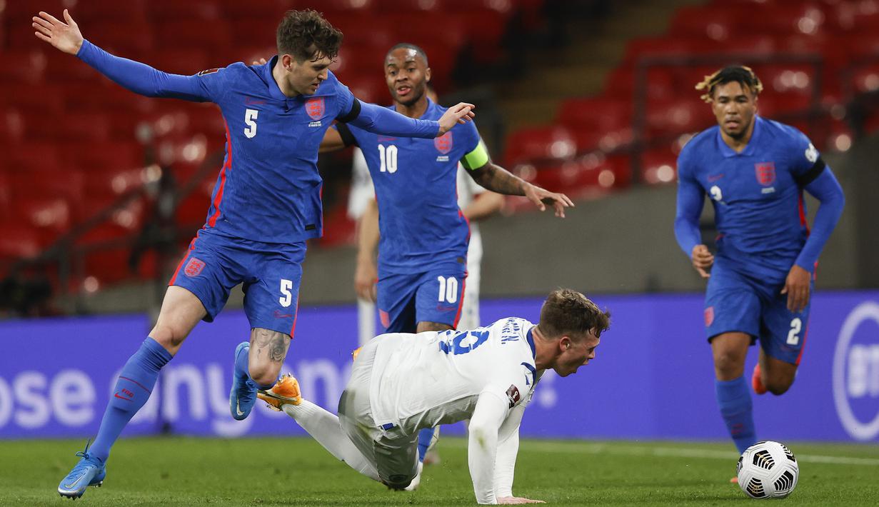 Striker San Marino, Nicola Nanni (kanan) terjatuh saat perebutan bola dengan bek Inggris, John Stones dalam laga Kualifikasi Piala Dunia 2022 Zona Eropa Grup I di Wembley Stadium, London, Kamis (25/3/2021). San Marino kalah 0-5 dari Inggris. (AP/Adrian Dennis/Pool)