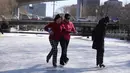 Seorang pria mengajari seorang perempuan menari di atas sepatu roda di kanal yang membeku saat Olimpiade Musim Dingin 2022 hampir berakhir di Beijing pada Sabtu, 19 Februari 2022. (AP Photo/Ng Han Guan)