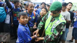 Petugas keamanan memasangkan penonton gelang tiket masuk pertandingan di Stadion Gelora Bandung Lautan Api (GLBA), Jawa Barat, Sabtu (15/4). Bobotoh penasaran ingin melihat aksi Essien dan Cole di laga perdana Maung Bandung. (Liputan6.com/Yoppy Renato)