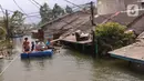 Warga melintas dengan perahu buatan saat banjir melanda perumahan Periuk Damai, Tangerang, Banten, Selasa (22/2/2021). Ratusan rumah masih terendam banjir sampai menyentuh ke atap rumahnya. (Liputan6.com/Angga Yuniar)