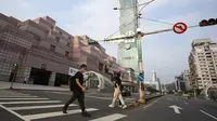 Warga memakai masker untuk melindungi diri penyebaran COVID-19 saat berjalan melewati Gedung Taipei 101 di Taipei, Taiwan, Sabtu (15/5/2021). Pandemi COVID-19 di Taiwan naik ke level tiga. (AP Photo/Chiang Ying-ying)