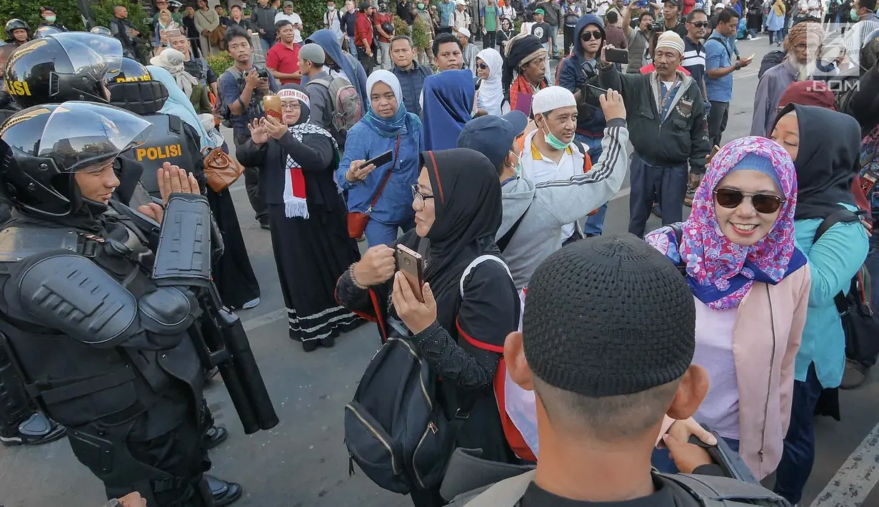 Sejumlah massa yang tergabung dalam Gerakan Pribumi Bersatu berbincang dengan Polisi dari kesatuan Brimob saat gelar doa bersama di depan kantor Bawaslu, Jakarta, Jumat (24/5/2019). Mereka datang untuk mendoakan para demonstran yang meninggal saat aksi 21-22 Mei. (Liputan6.com/Herman Zakharia)