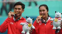 ganda campuran Indonesia Christopher Rungkat (kiri) dan Aldila Sutjiadi menggigit medali emas pada upacara penganugerahan medali seusai menang.