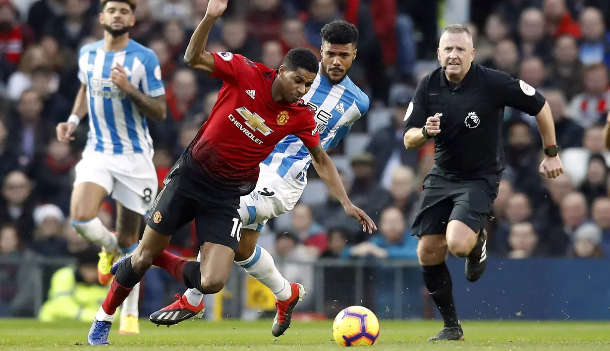 Penyerang Manchester United, Marcus Rasford, berusaha melewati pemain Huddersfield pada laga Premier League di Stadion Old Trafford, Rabu (26/12). Manchester United menang 3-1 atas Huddersfield. (AP/Martin Rickett)