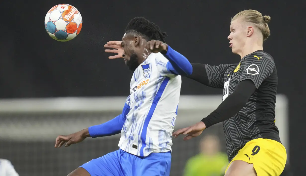 Bek Hertha Berlin Jordan Torunarigha berebut bola dengan penyerang Borussia Dortmund Erling Haaland pada laga pekan ke-17 Liga Jerman di Olympiastadion, Minggu (19/12/2021) dinihari WIB. Tuan rumah Hertha Berlin mempermalukan Dortmund dengan skor 3-2. (AP Photo/Michael Sohn)