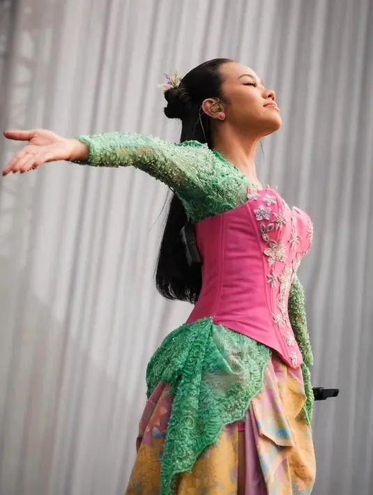 Potongan asimetris di bagian bawah memberi siluet dinamis yang modern, sementara kain batik warna pastel yang disampirkan membalut kakinya menambah sentuhan etnik yang kuat namun tetap playful.   [@yurayunita].