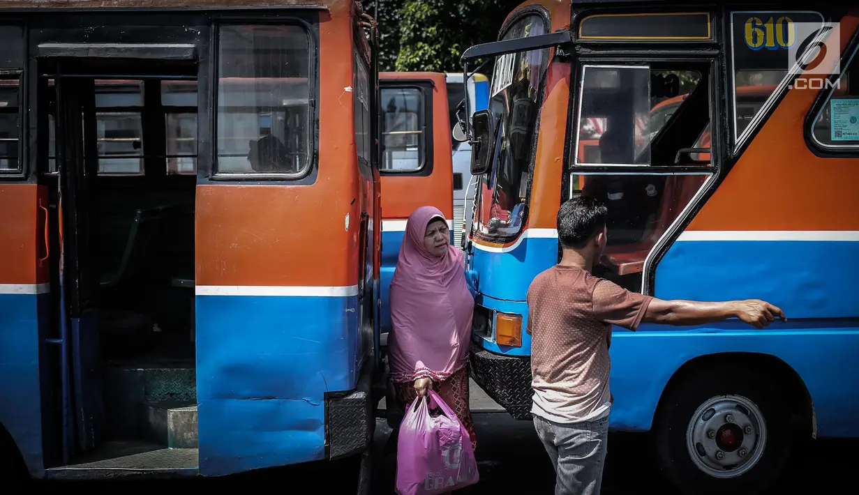 Seorang wanita melintas diantara Metromini di Terminal Blok M, Jakarta, Rabu (26/7). Menurut pihak Dishub DKI, revitalisasi tersebut melibatkan langsung para pemilik kendaraan Metromini. (Liputan6.com/Faizal Fanani)