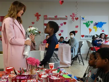 Melania Trump menerima buket bunga dari Amani (13) asal Kenya dalam kunjungannya di rumah sakit National Institutes of Health, Maryland, Kamis (14/2). Melania Trump menghabiskan momen Hari Valentine bersama anak-anak di rumah sakit.  (AP/Susan Walsh)