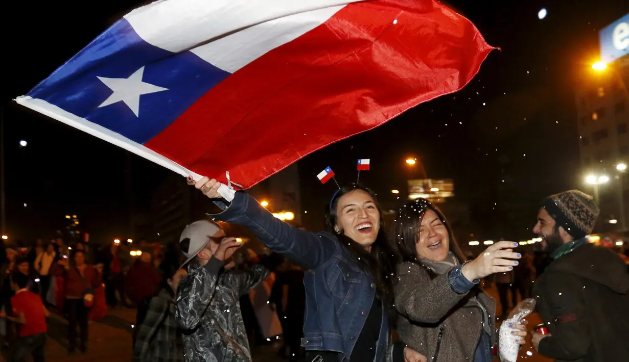 Suporter Chili mengibarkan bendera nasional Chili merayakan kemenangan Chile atas Argentina di final Copa America 2015 di Santiago, (4/7/2015). Chili menang lewat adu penalti atas Argentina dengan skor 4-1. (REUTERS/Rodrigo Garrido)