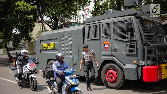 Pengendara sepeda motor melintasi mobil water cannon yang disiagakan di Kantor Komisi Pemilihan Umum (KPU), Jakarta, Kamis (18/4). Hal tersebut dilakukan untuk mengantisipasi ancaman keamanan usai Pemilu 2019. (Liputan6.com/Faizal Fanani)