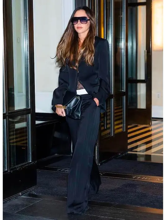 Potret penuh pesona Victoria Beckham dalam work wear serba hitam. Atasan hitam terstruktur dipadu wide leg pants yang juga berwarna hitam. Gayanya semakin keren dengan clutch hitam dan sunglasses. [Foto: Instagram/victoriabeckham]