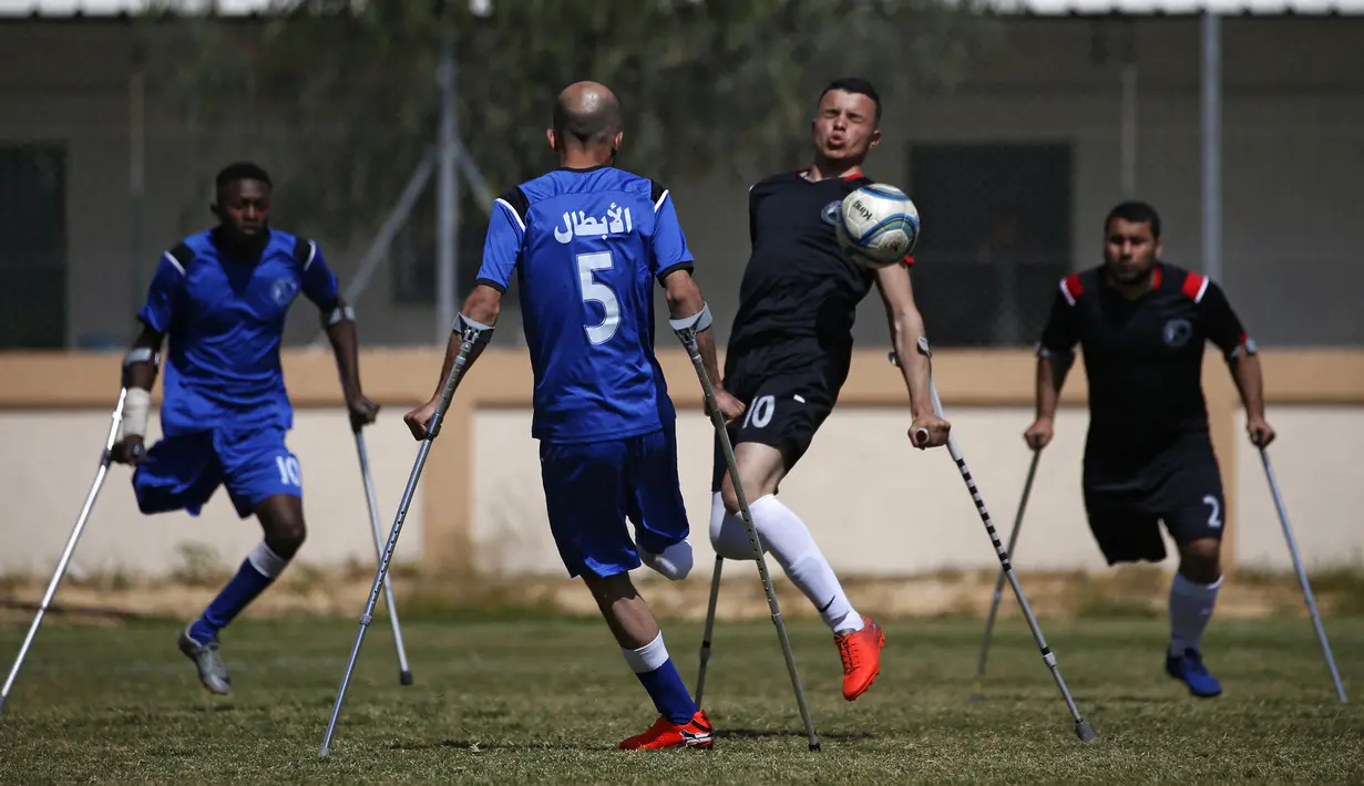 Seorang pemain klub Al-Jazeera (hitam) mengontrol bola dalam pertandingan final kejuaraan lokal sepak bola korban amputasi melawan Al-Abtal yang diselenggarakan oleh Komite Palang Merah Internasional (ICRC), di tengah pandemi COVID-19, di Kota Gaza, Palestina, (18/3/2021). (AFP/Mohammed Abed)