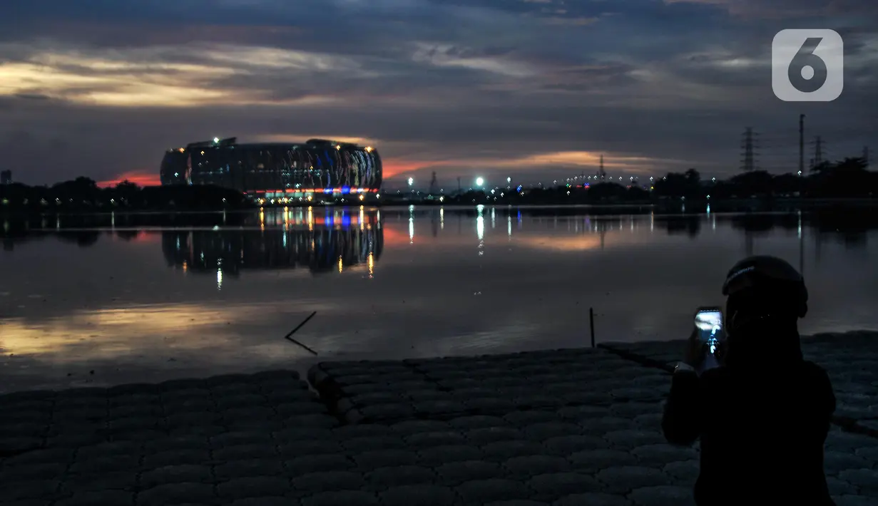 Warga memfoto gemerlap Jakarta International Stadium (JIS) dari Waduk Cincin, Papanggo, Jakarta Utara, Rabu (16/3/2022). PT Jakarta Propertindo (Jakpro) menargetkan pembangunan JIS rampung dan siap dibuka pada April 2022. (merdeka.com/Iqbal S. Nugroho)
