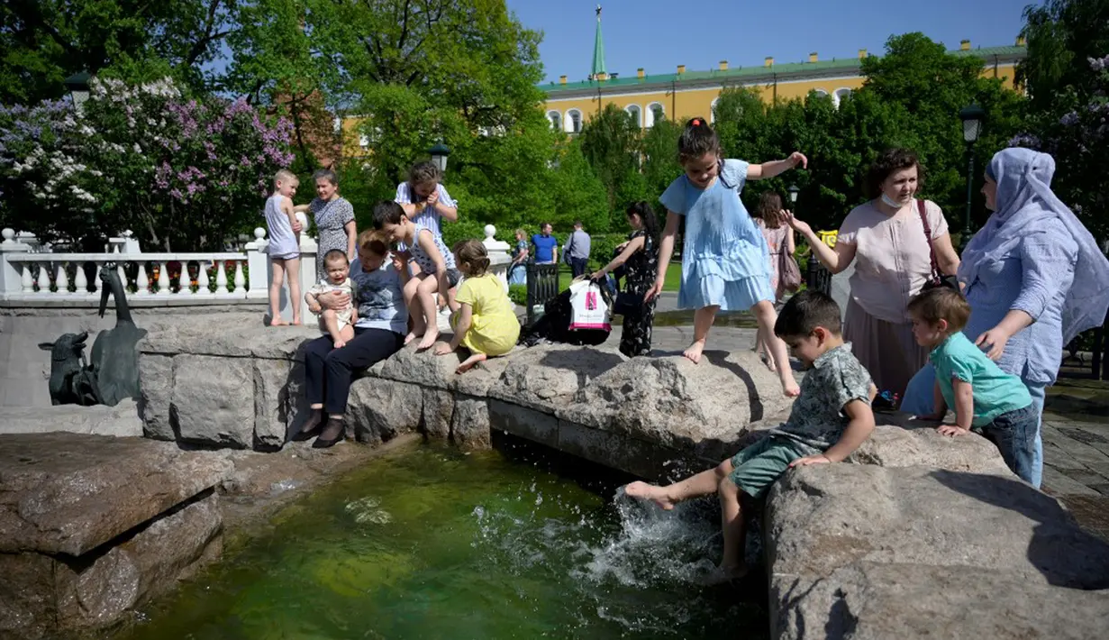 Orang-orang menikmati musim semi yang panas dekat air mancur di luar Kremlin, Moskow, Rusia, Selasa (18/5/2021). Suhu di Moskow telah mencapai 31 derajat Celcius. (Natalia KOLESNIKOVA/AFP)