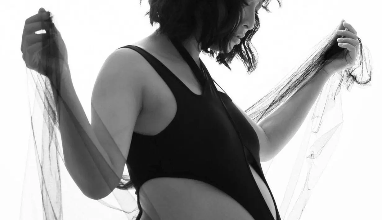 Bernuansa hitam putih, Rinni terlihat mengenakan cut-out bodysuit yang memperlihatkan baby bump-nya. [instagram/rinni_w]