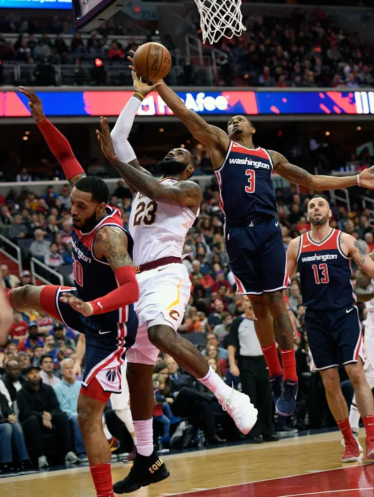 Pebasket Cleveland Cavaliers, LeBron James dan pebasket Washington Wizards, Bradley Beal berebut bola pada lanjutan NBA di Verizon Center, Minggu (17/12). James menyampaikan protes terhadap Presiden Donald Trump lewat sepatu beda warnanya. (AP/Nick Wass)