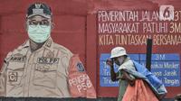 Pejalan kaki melintasi mural bertemakan Imbauan Protokol Kesehatan Covid-19 di kawasan Bukit Duri, Jakarta, Minggu (25/10/2020). Gubernur DKI Anies Baswedan kembali memperpanjang Pembatasan Sosial Berskala Besar (PSBB) masa transisi hingga 8 November 2020. (merdeka.com/Iqbal Nugroho)
