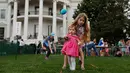Caroline Earnshaw (10) membantu adiknya menggelindingkan telur saat lomba perayaan Paskah di halaman Gedung Putih, Washington, Senin (17/4). Lomba yang digelar setiap tahun ini merupakan lomba menggelindingkan telur yang ke-139. (AP Photo/Carolyn Kaster)