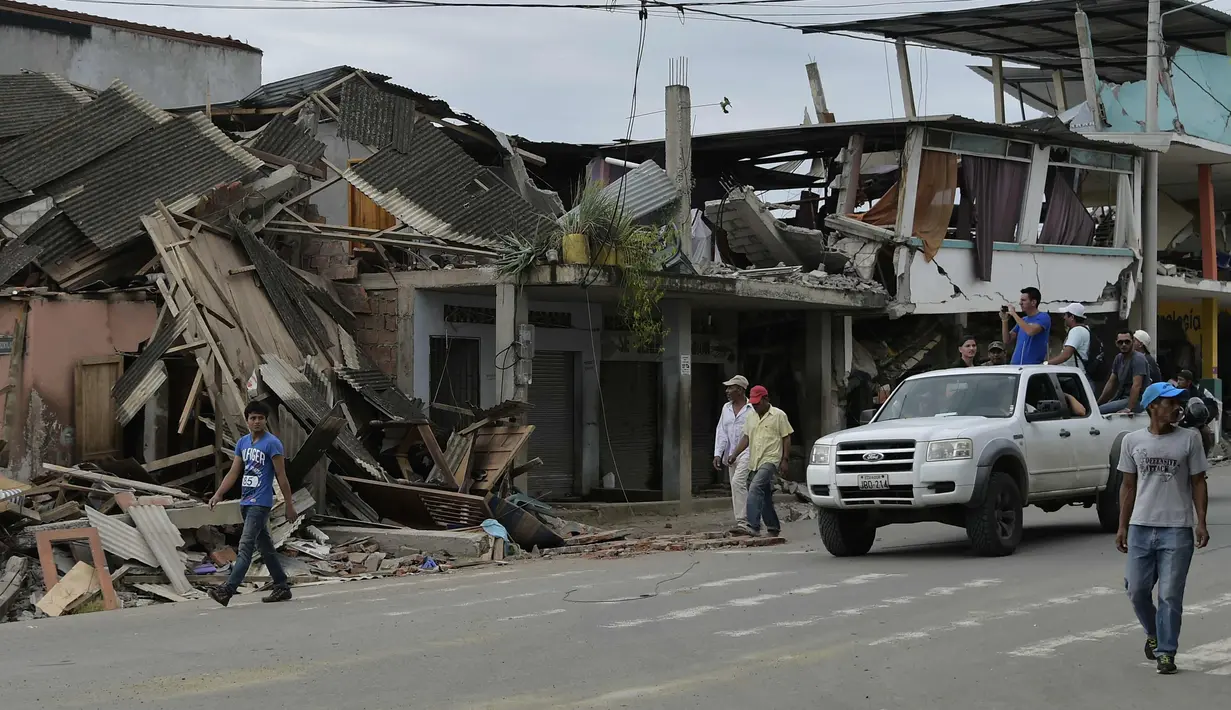 Warga melewati reruntuhan bagunan pasca gempa berkekuatan 7,8 yang melanda Pedernales, Ekuador, Minggu (17/4). Tim penyelamat menggunakan traktor dan tangan kosong untuk mencari para korban lainnya yang terkubur puing-puing bangunan. (RODRIGO Buendia/AFP)