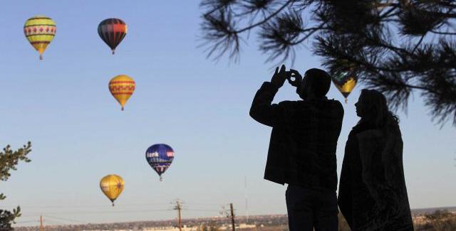 Seorang pengunjung sedang mengabadikan moment cantik terbangnya balon udara | (c) Merdeka.com
