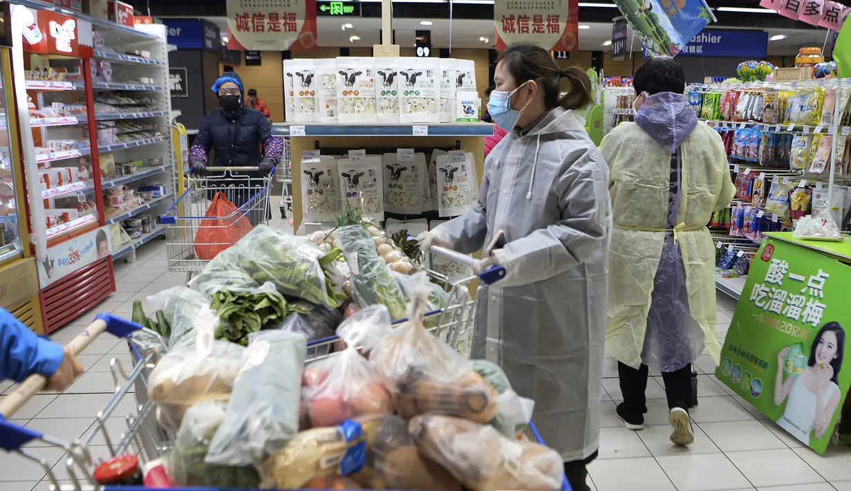 Seorang wanita mengenakan jas hujan dan masker membeli makanan di sebuah supermarket di Wuhan di provinsi Hubei, China tengah, Senin, (10/2/2020). China melaporkan kenaikan angka kematian akibat wabah virus corona. (Chinatopix via AP)