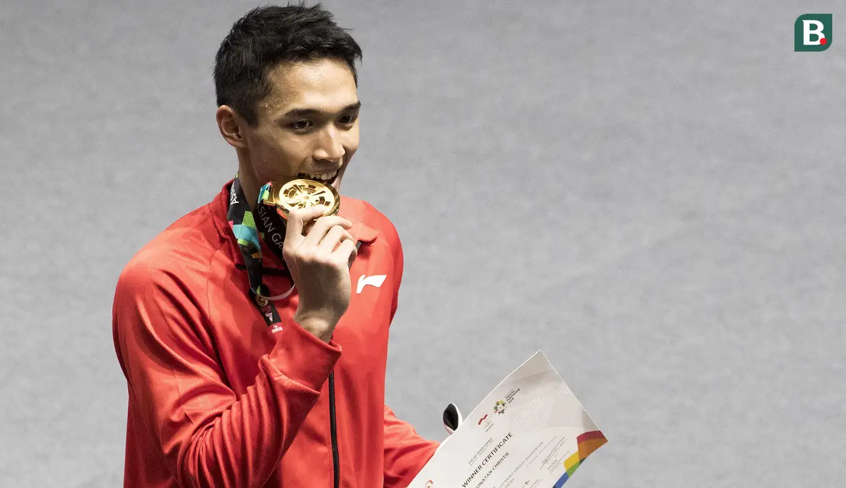 Pebulutangkis Indonesia, Jonatan Christie, menggigit medali usai final tunggal putra bulutangkis di Istora Senayan, Selasa (28/8/2018). Jonatan menang 21-18, 20-22, 21-15 atas wakil China Taipei, Chou Tien Chen. (Bola.com/Peksi Cahyo)