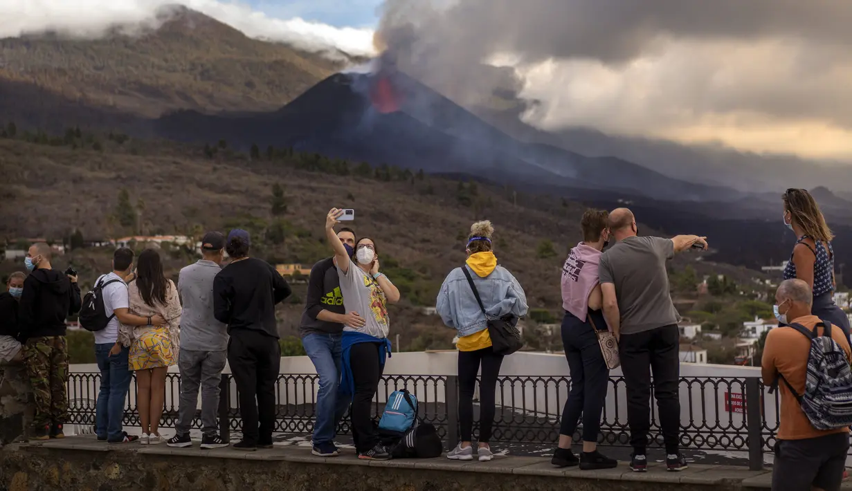 Wisatawan melihat dan berswafoto dengan latar gunung berapi yang meletus di Canary, Pulau La Palma, Spanyol, 26 Oktober 2021. Para pejabat mengatakan gunung berapi yang meletus selama lima minggu terakhir di Pulau La Palma lebih aktif dari sebelumnya. (AP Photo/Emilio Morenatti)