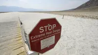 Tanda peringatan bahaya panas ekstrem di Badwater Basin, Taman Nasional Death Valley, California, Kamis (17/6/2021). Sebagian besar Amerika Serikat bagian barat bersiap menghadapi rekor gelombang panas minggu ini. (Patrick T. FALLON/AFP)
