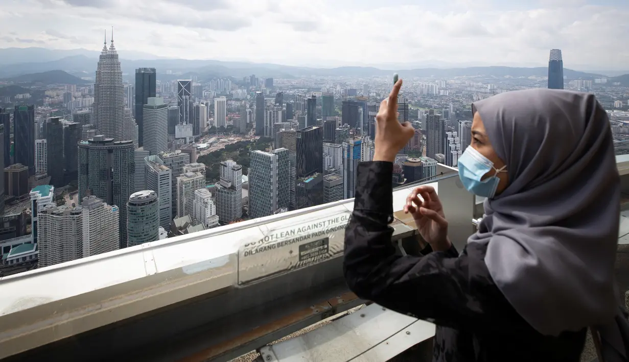 Seorang turis dengan mengenakan masker mengambil gambar dari dek obseravsi di Menara Kuala Lumpur di Kuala Lumpur, Rabu (1/7/2020). Malaysia memasuki pelonggaran Perintah Kontrol Gerakan (MCO) setelah tiga bulan pembatasan karena virus corona Covid-19. (AP Photo/Vincent Thian)