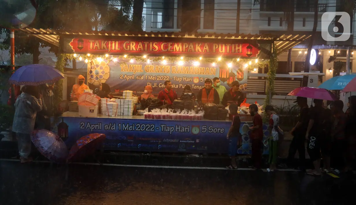 Sejumlah warga antre untuk mendapat takjil gratis di Jalan Cempaka Putih Tengah XXI, Jakarta, Selasa (5/4/2022). Hujan deras yang mengguyur kawasan tersebut tidak menghalangi warga untuk mendapatkan takjil gratis. (Liputan6.com/Herman Zakharia)