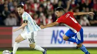 Pemain Argentina, Lionel Messi (kiri) berusaha melepaskan diri dari adangan pemain Paraguay, Junior Alonso (kanan) dalam lanjutan Kualifikasi Piala Dunia Zona CONMEBOL, Jumat (8/10/2021) dini hari WIB. (AP Photo/ Jorge Saenz)