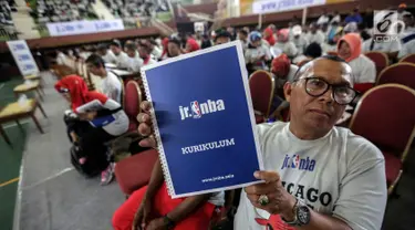 Seorang guru olahraga menunjukkan buku kurikulum pelatihan pendidikan basket dari Akademi Pelatih Junior NBA di GOR Ciracas, Jakarta, Rabu (24/1). Pendidikan ini ditujukan kepada lebih dari lima ribu guru olahraga di Jakarta. (Liputan6.com/Faizal Fanani)