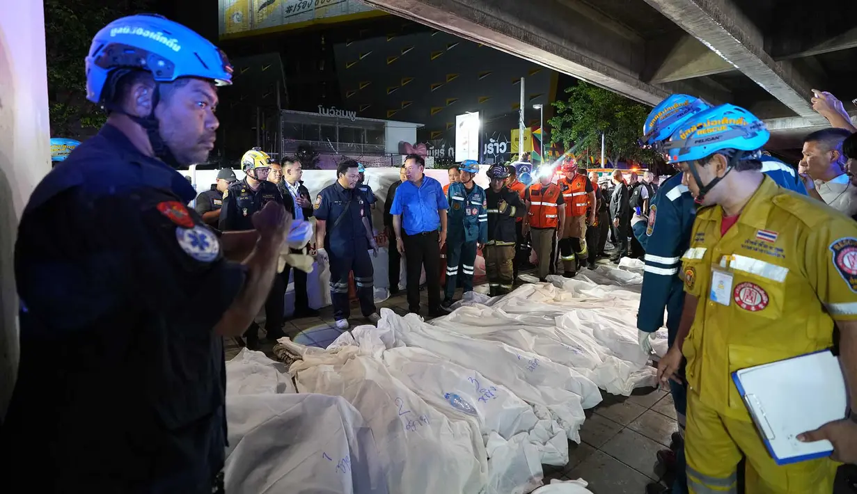 Perdana Menteri Thailand Anutin Charnvirakul, mengenakan pakaian biru, memeriksa lokasi kebakaran sementara jenazah para korban diletakkan berjejer di Bangkok, Thailand, Senin, 13 Juli 2026. (AP Photo/Sakchai Lalit)
